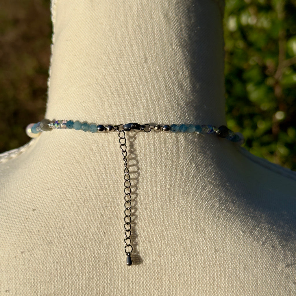 Necklace with blue beads and chain on a mannequin against a natural background
