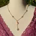 Necklace with moon and star pendants on a mannequin wearing a lace garment outdoors.