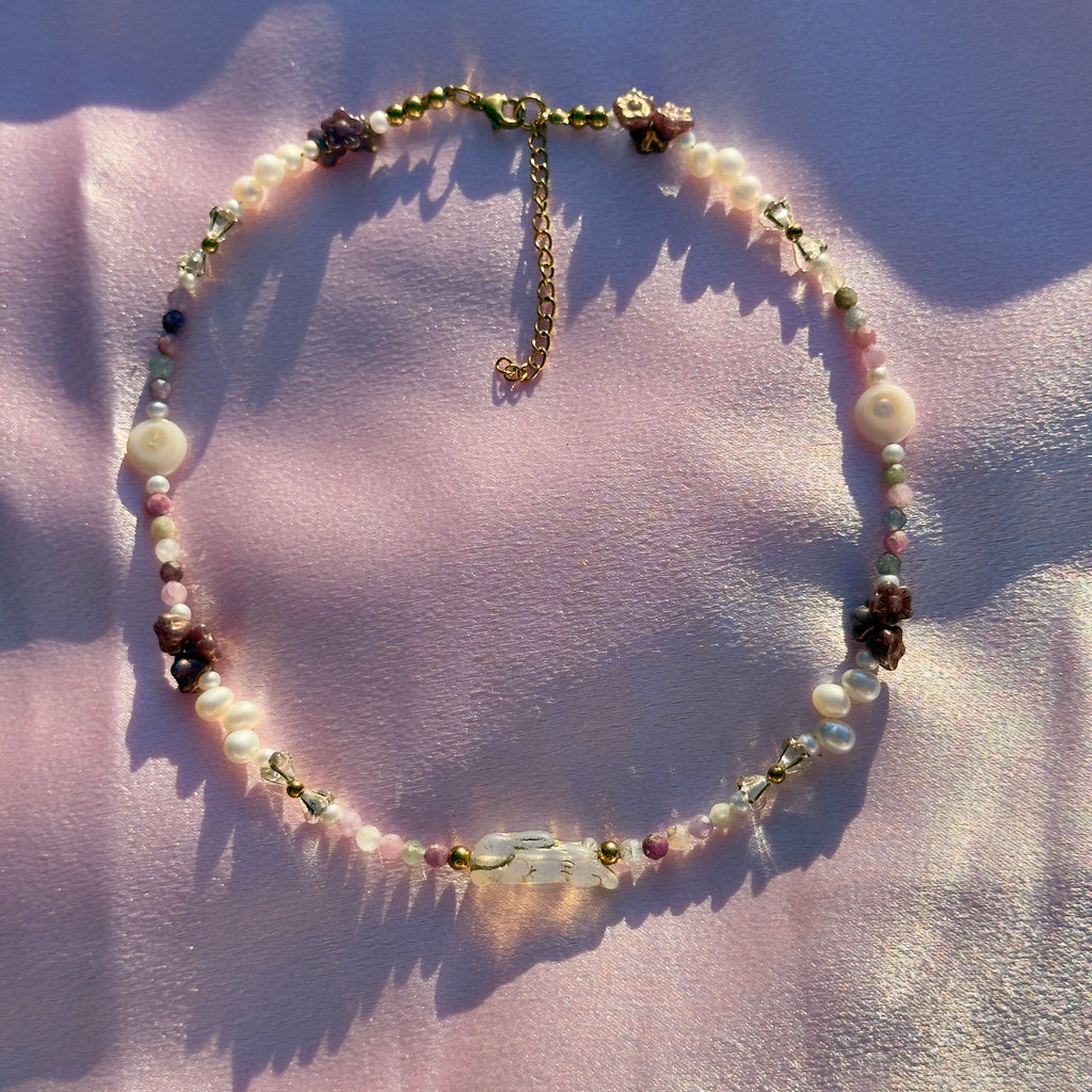 Necklace with pearls and gemstones on a pink fabric background