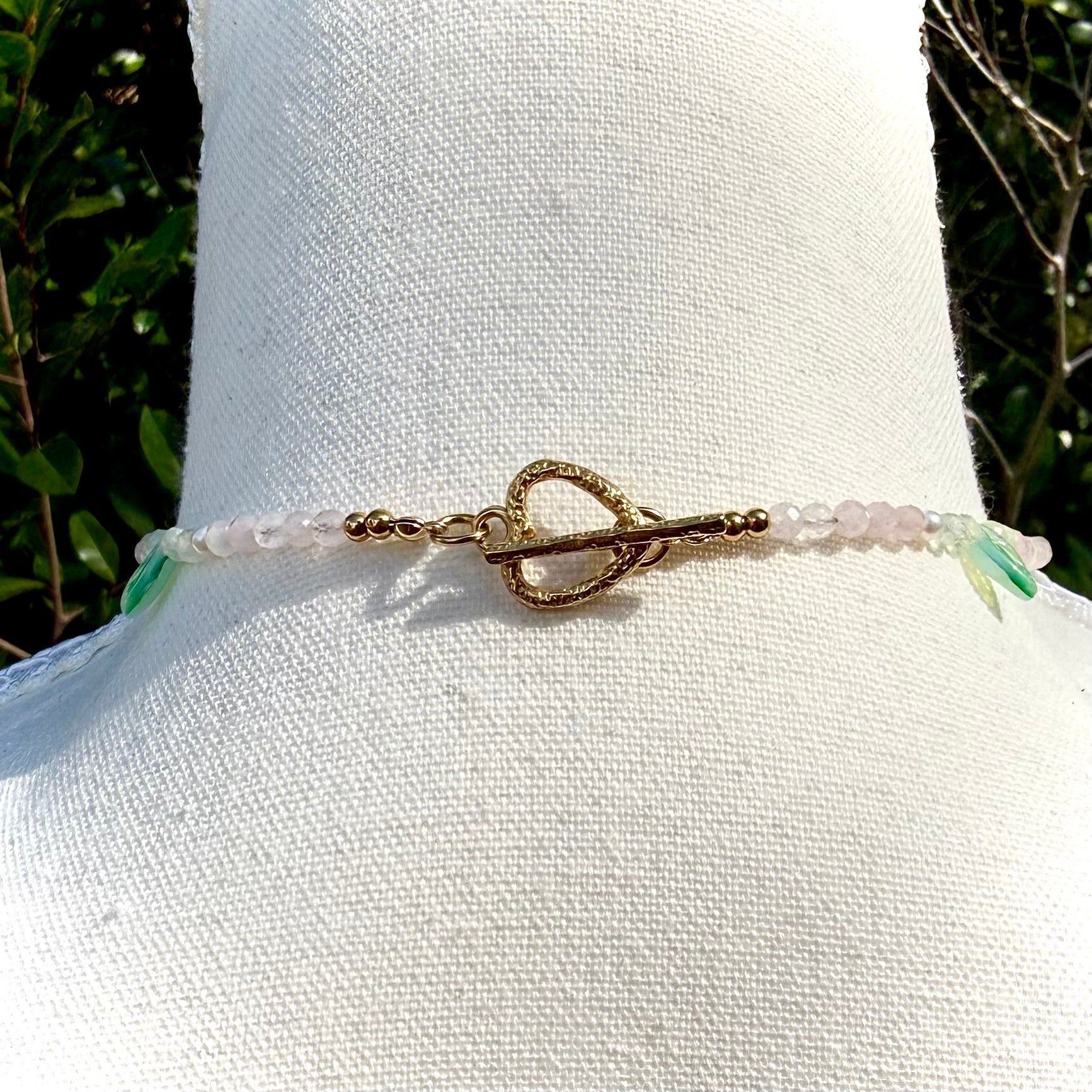 Back of necklace with heart toggle on a mannequin against a natural background
