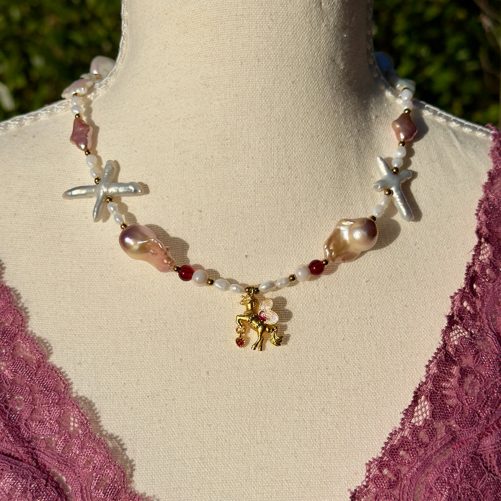 Necklace with starfish and pearl-like beads on a mannequin with a pink lace garment.