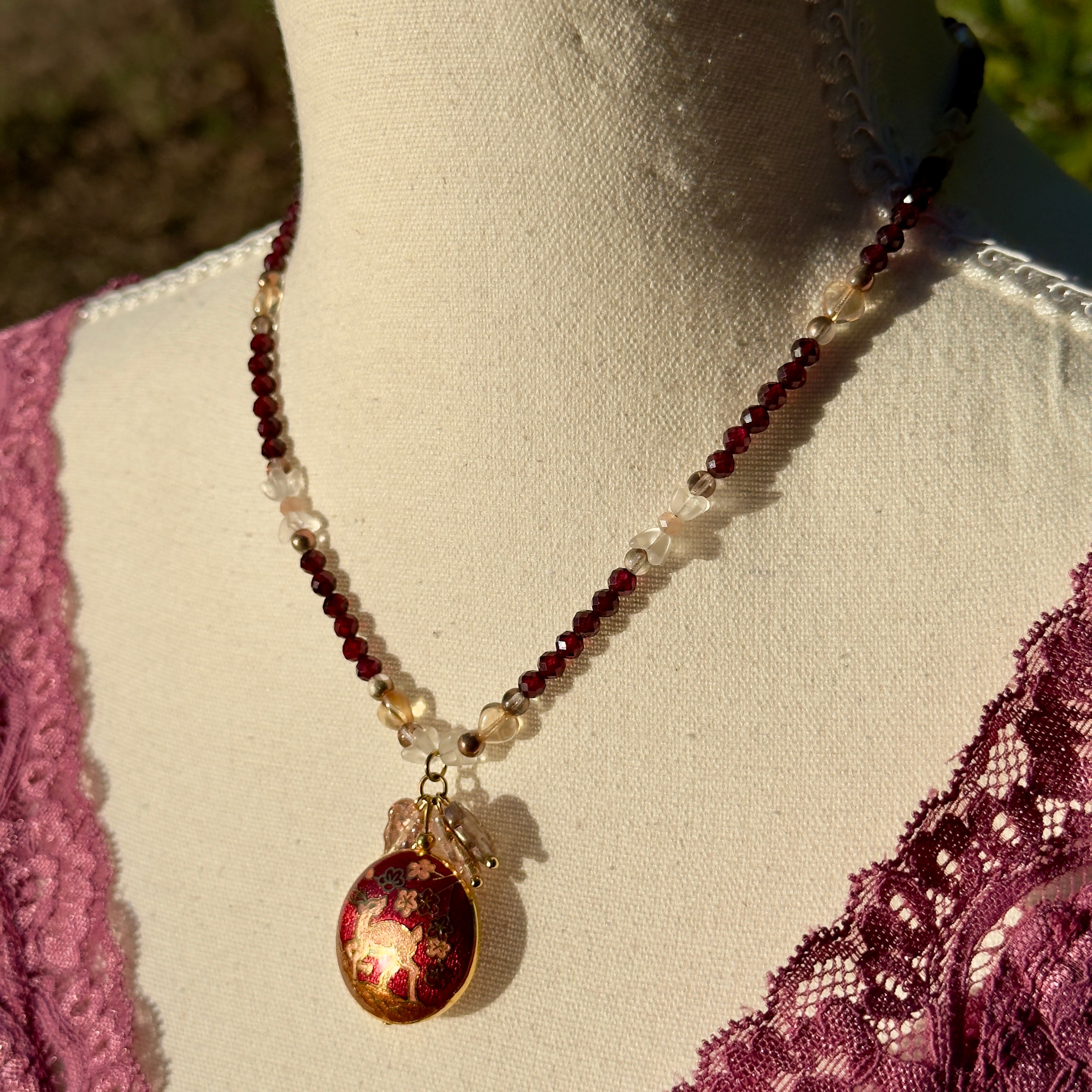 Necklace with red and gold pendant on a mannequin with lace details