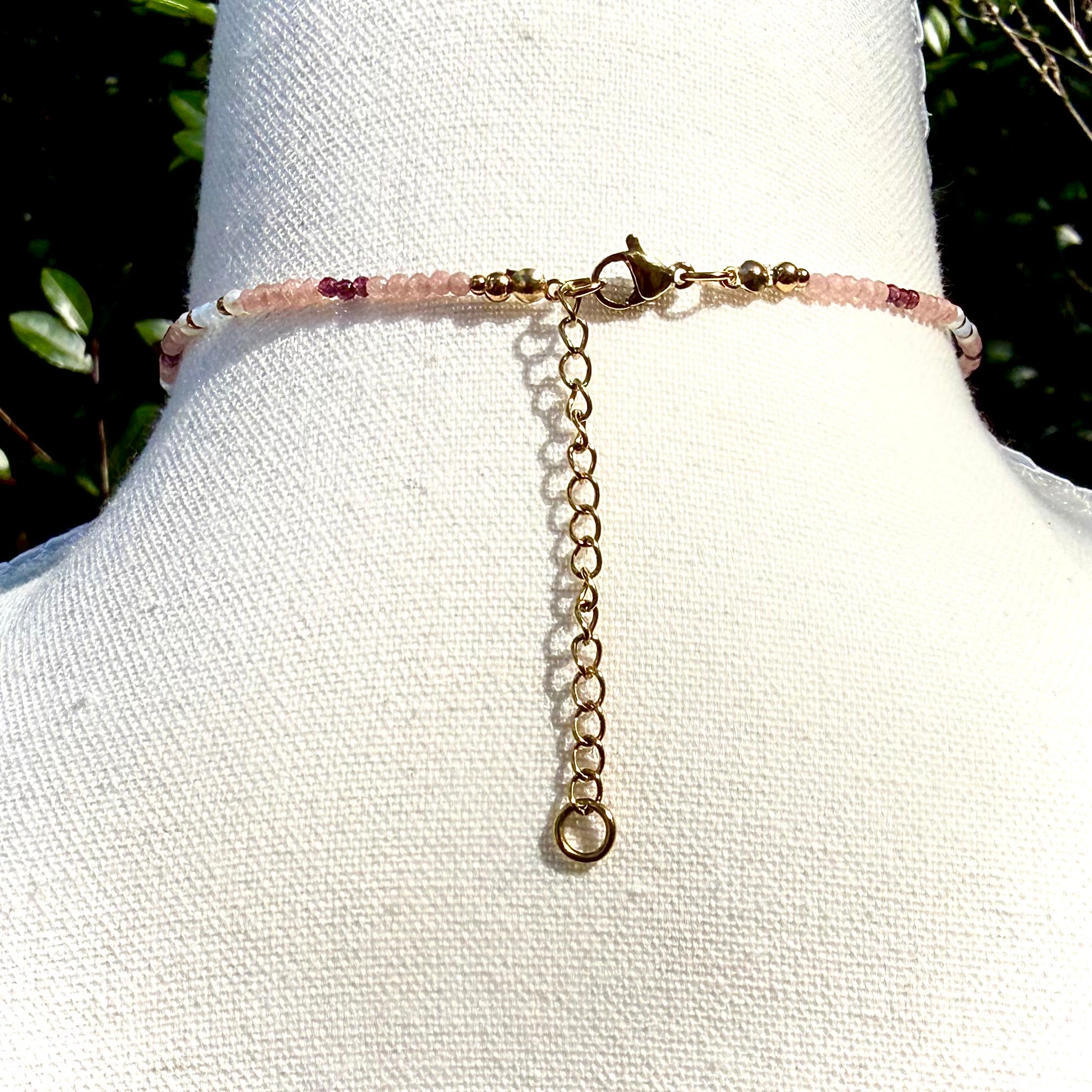 Back of Necklace with pink beads and gold chain on a mannequin bust.