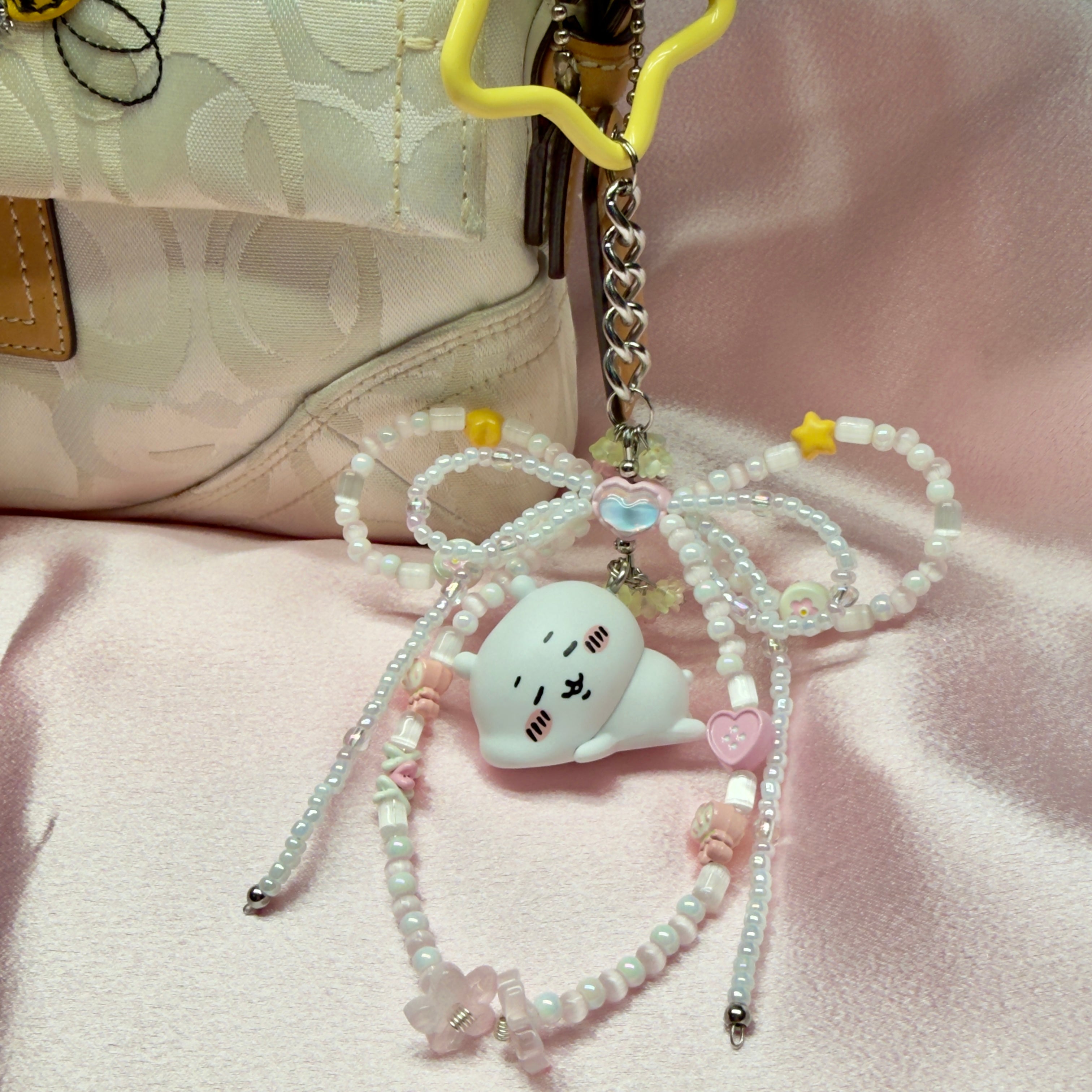 Cute cat-shaped phone charm with beads on a pink background