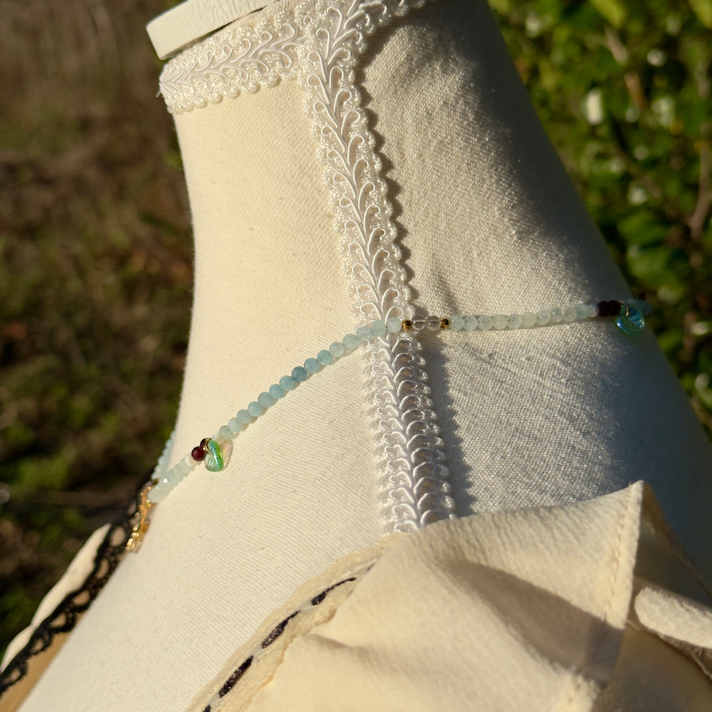 Close-up of a necklace on a mannequin against a natural background.