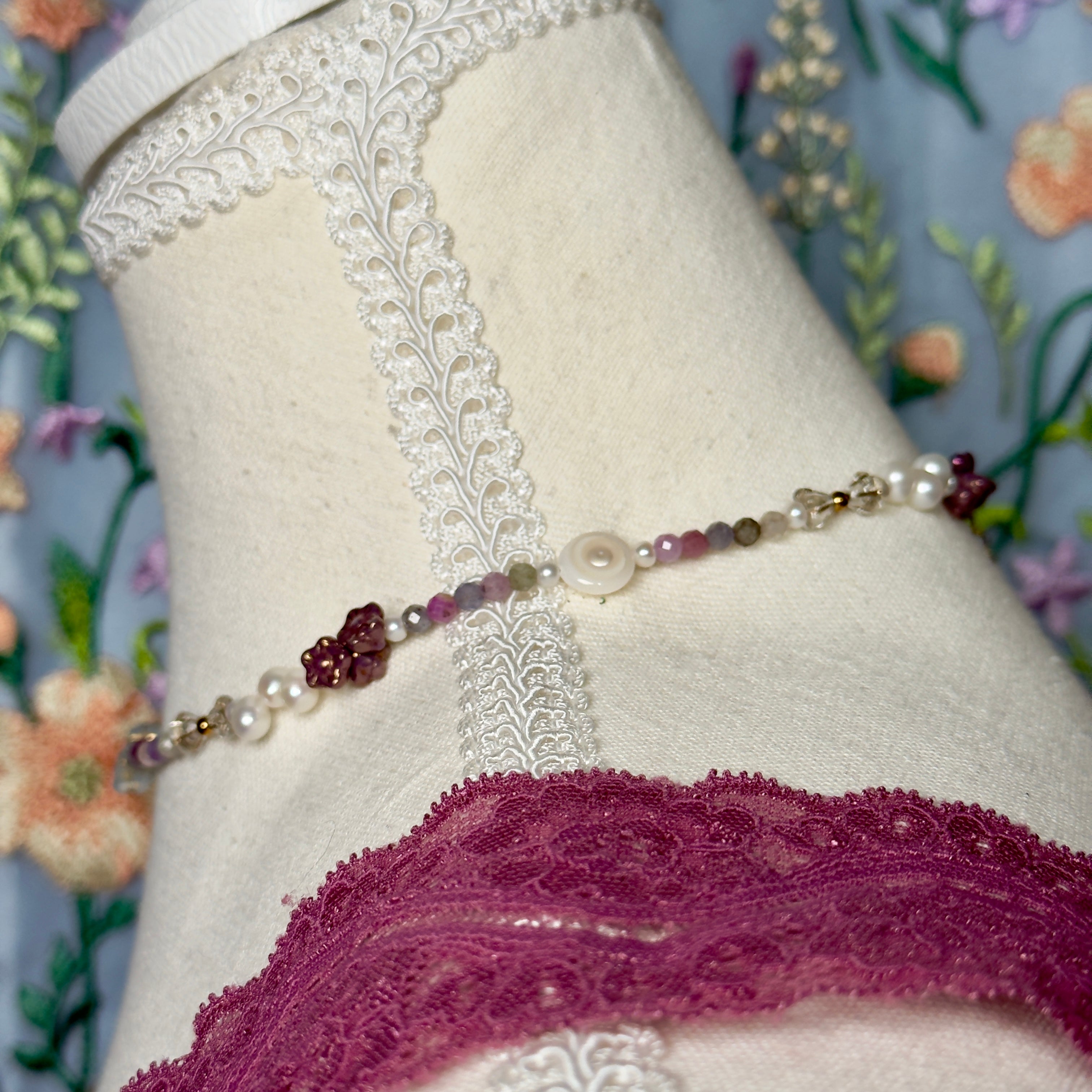 Pearl and gemstone necklace on a mannequin with floral background