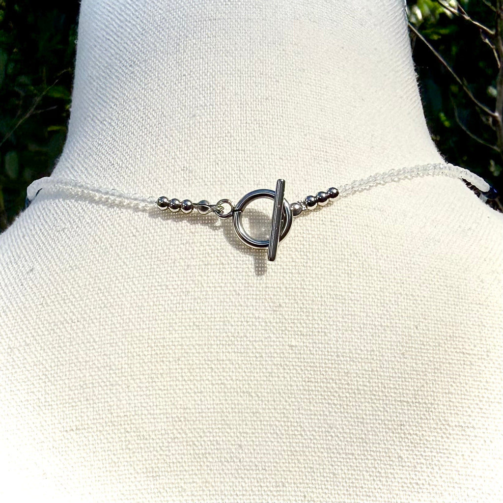 Necklace with a unique clasp on a mannequin bust against a natural background