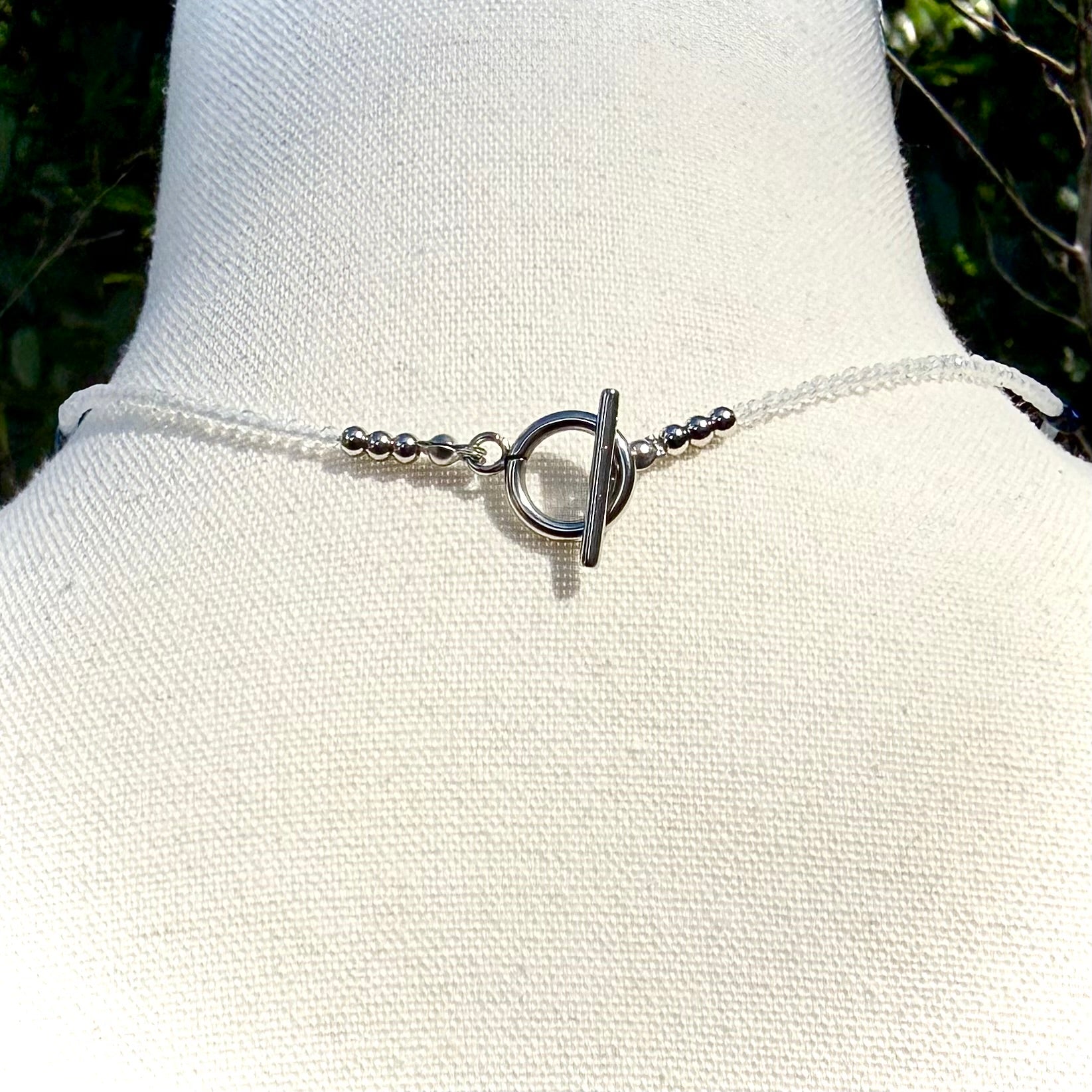 Necklace with a unique clasp on a mannequin bust against a natural background