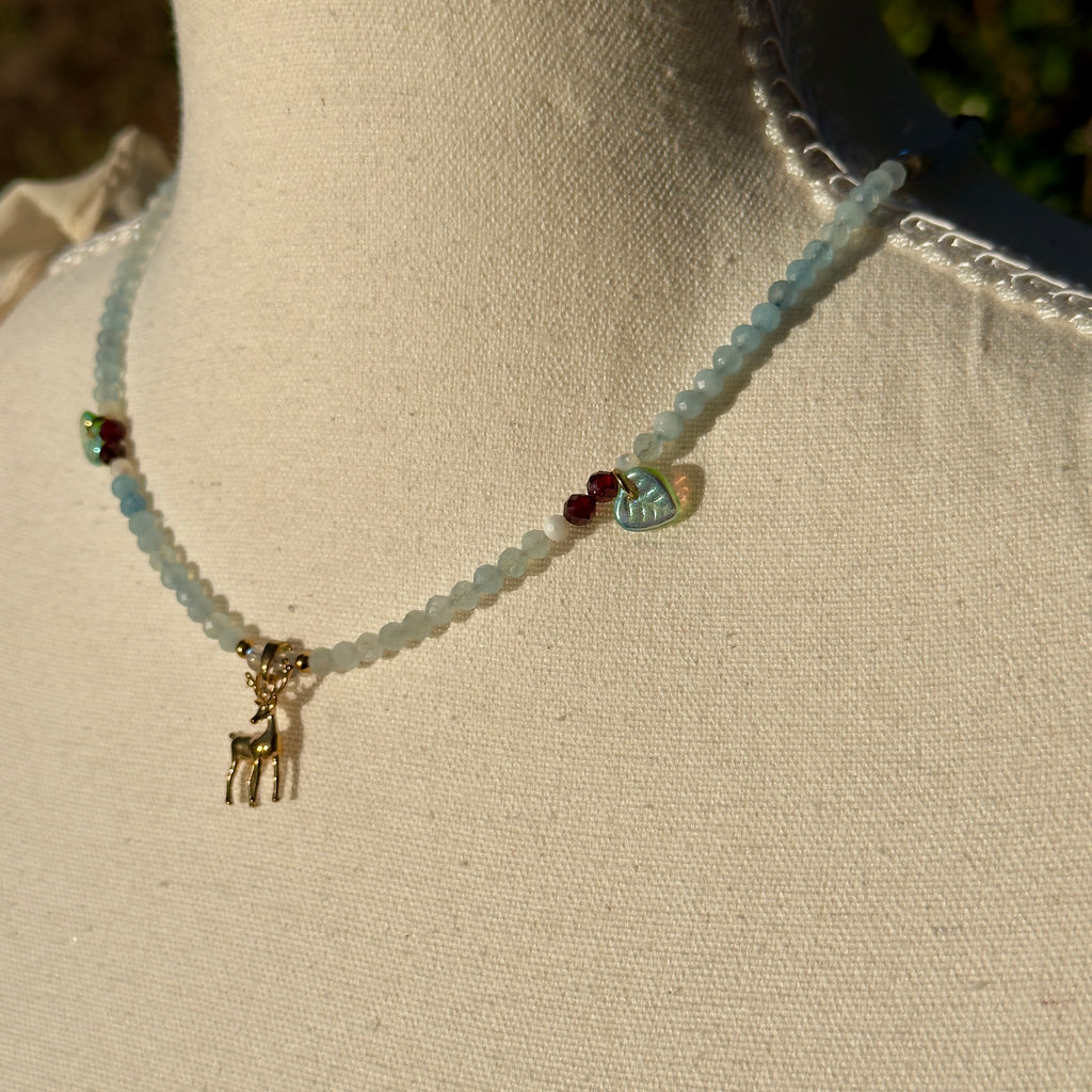 Necklace with a small deer charm on a mannequin neck against a neutral background