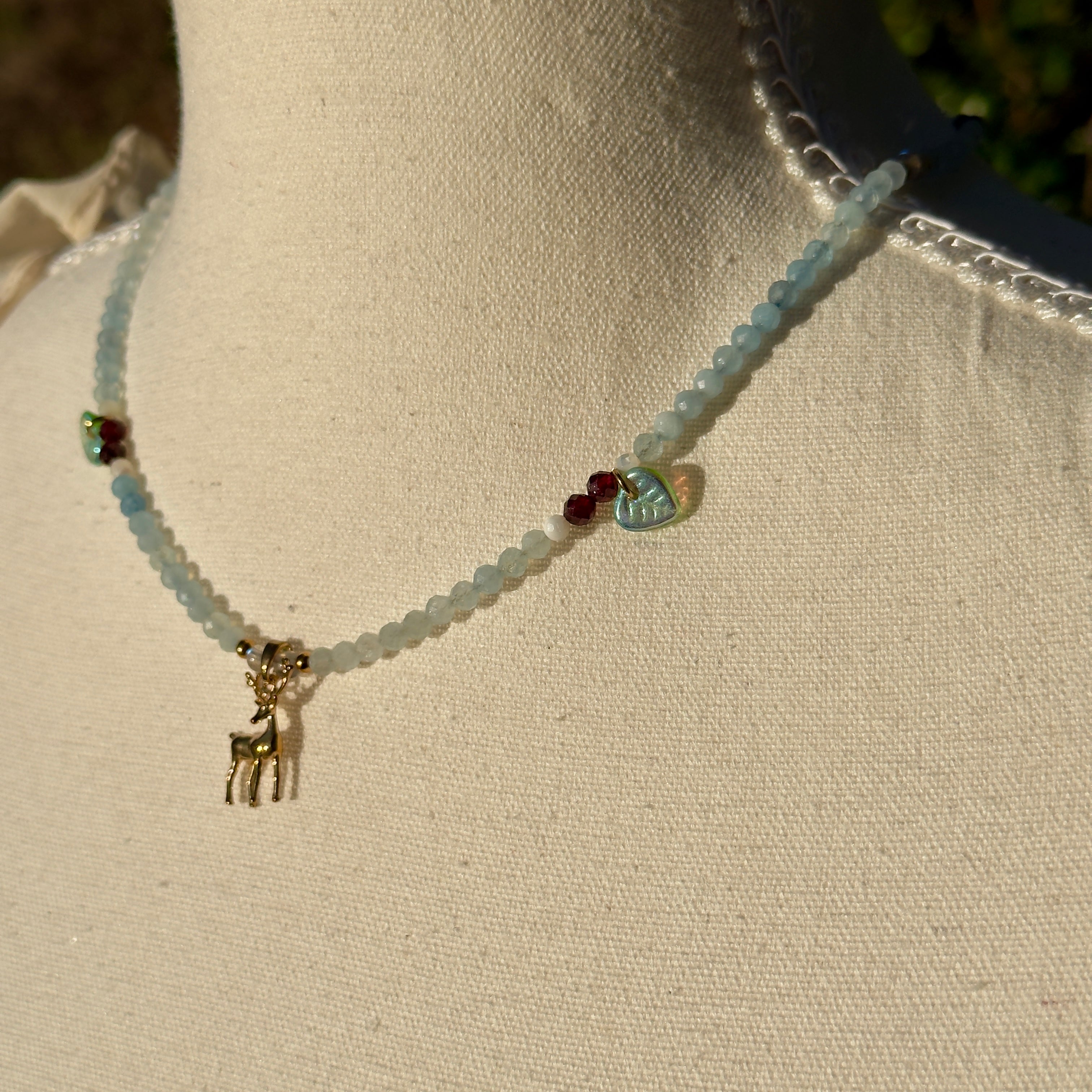 Necklace with a small deer charm on a mannequin neck against a neutral background