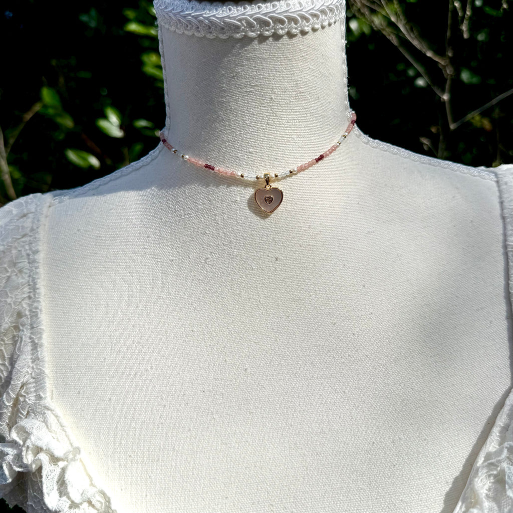 Necklace with a heart-shaped pendant on a mannequin against a blurred natural background