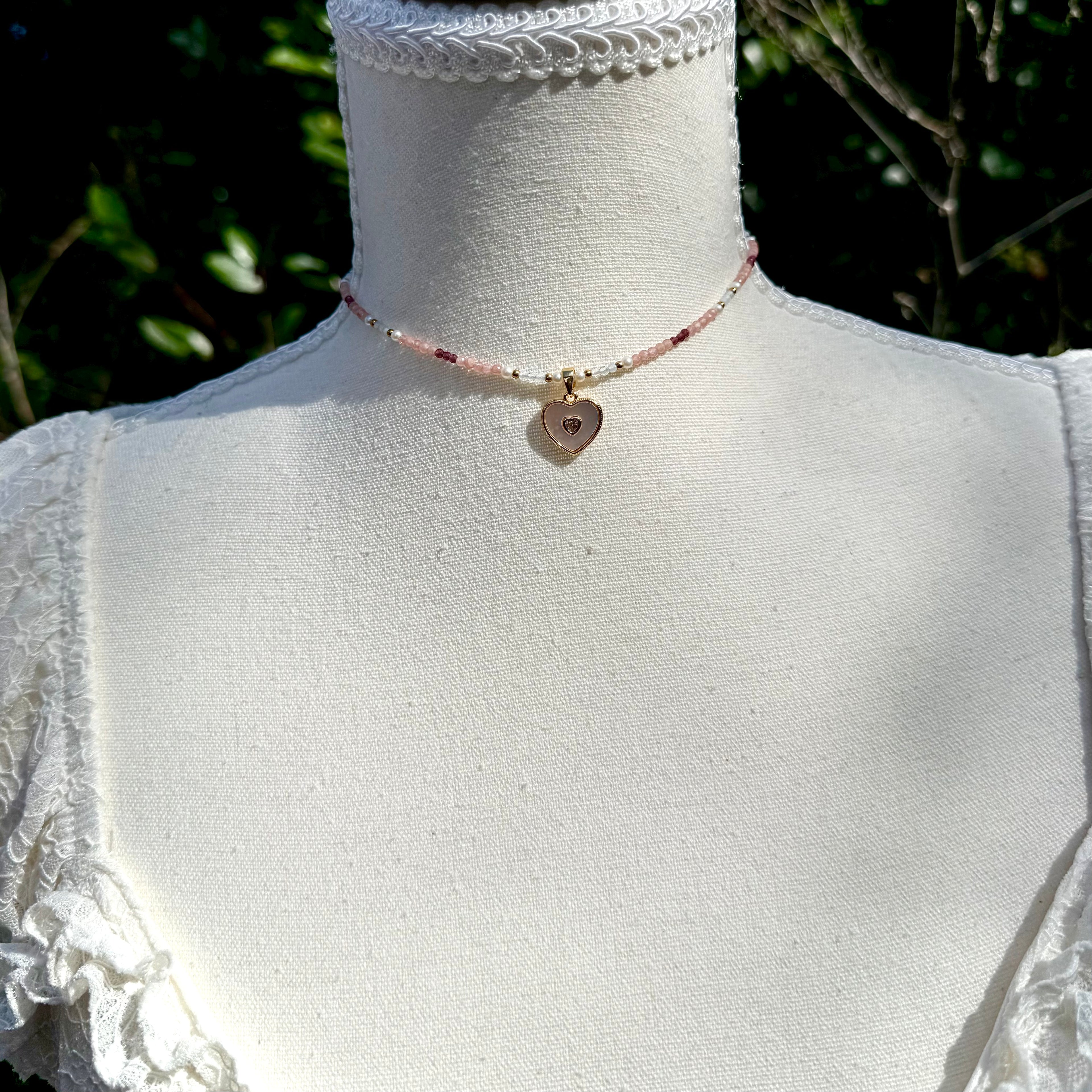 Necklace with a heart-shaped pendant on a mannequin against a blurred natural background