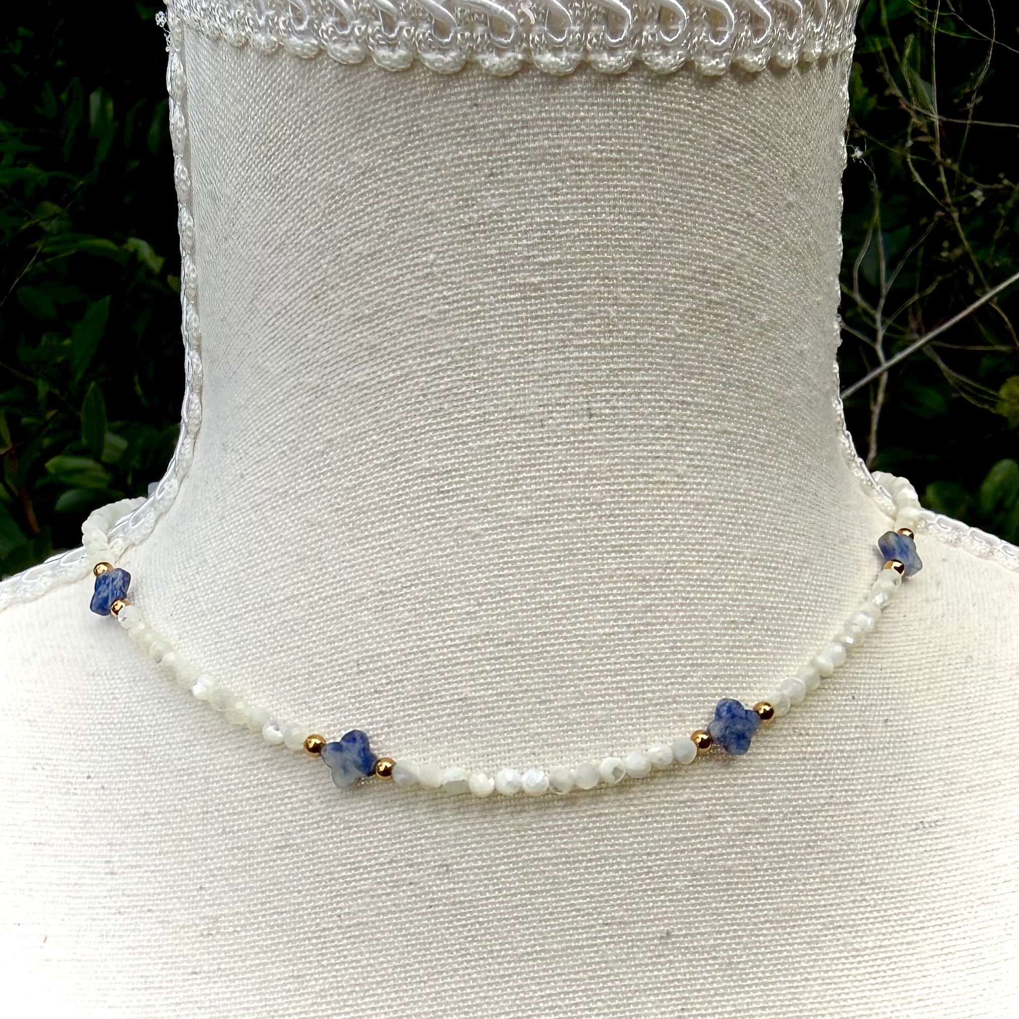 Crystal  necklace with blue beads on a mannequin against a natural background