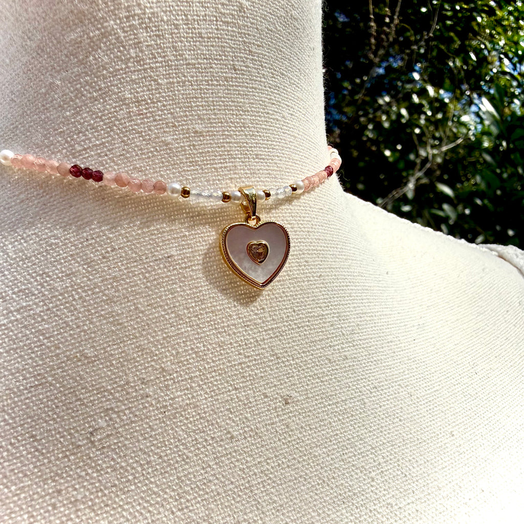 Necklace with heart-shaped charm on a mannequin arm against a natural background