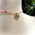 Necklace with heart-shaped charm on a mannequin arm against a natural background