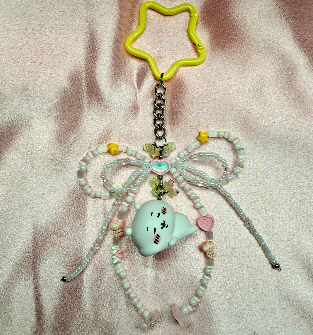 Decorative keychain with beads and a character on a textured surface