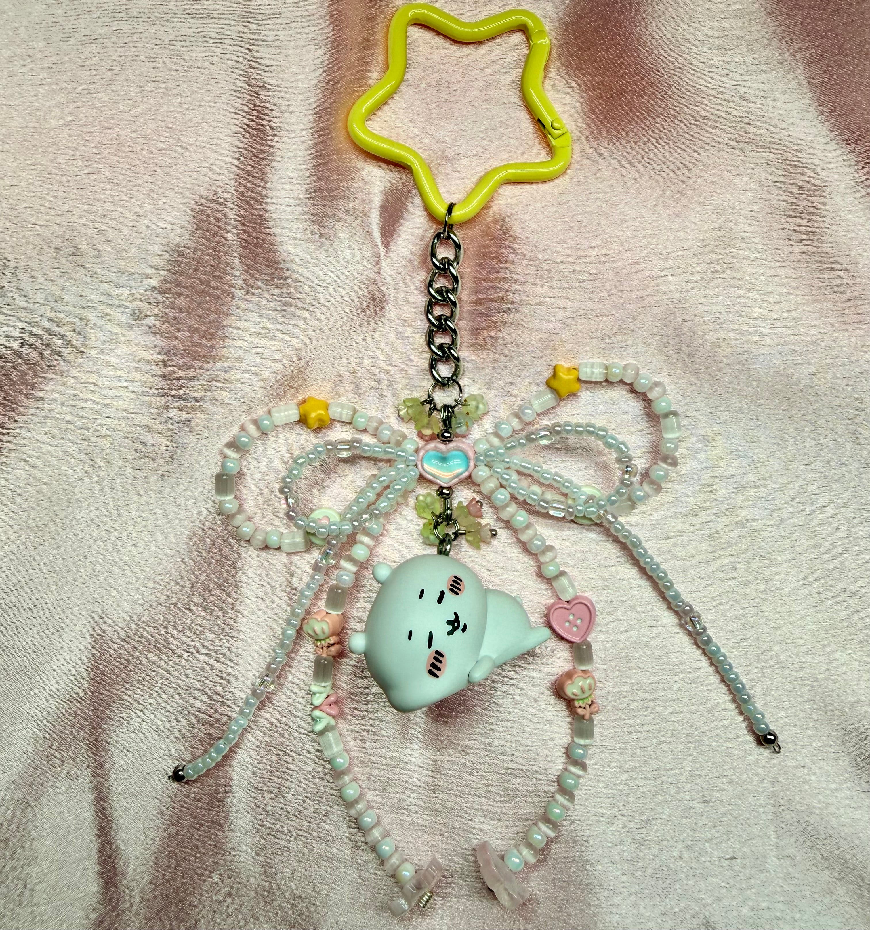 Decorative keychain with beads and a character on a textured surface