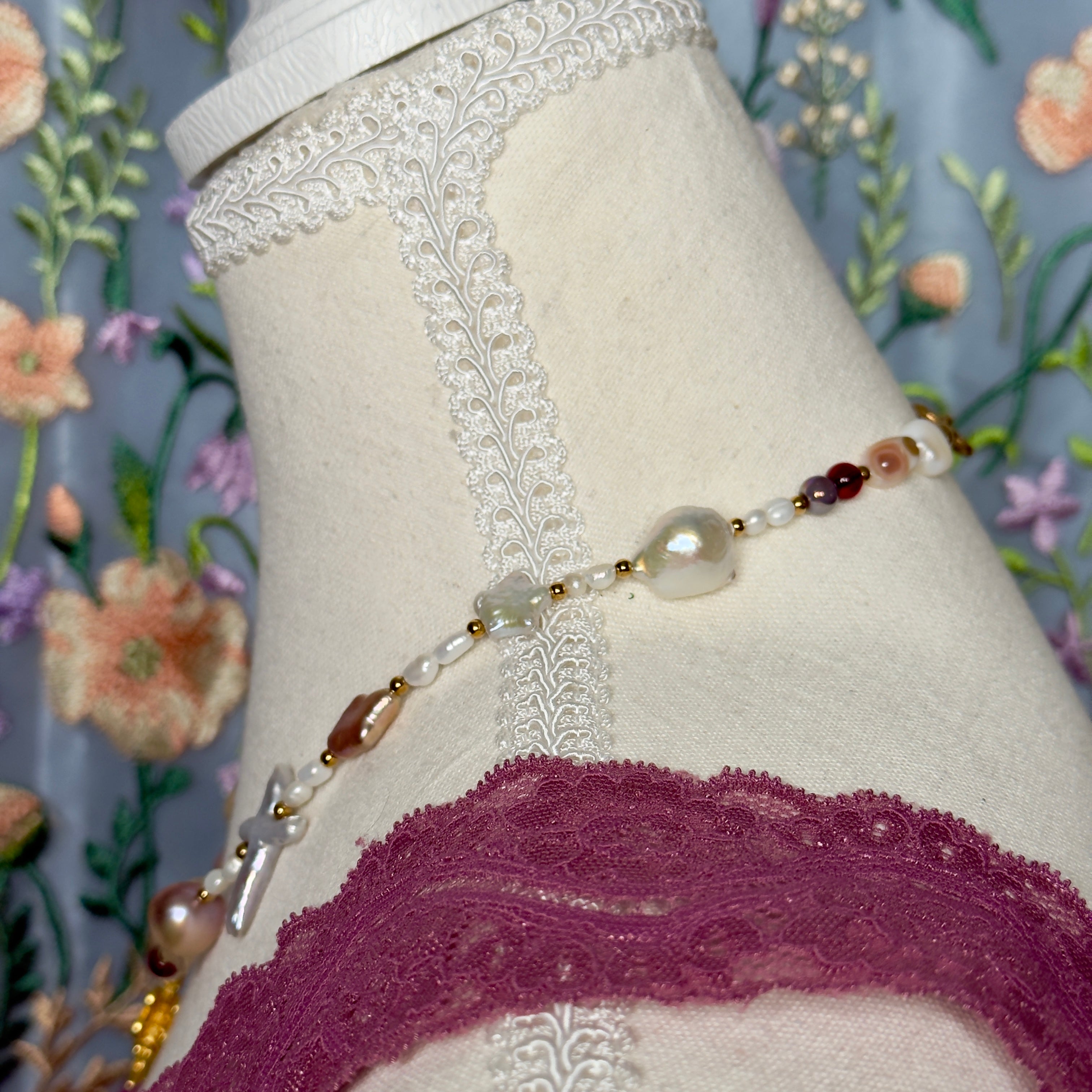 Necklace with beads and pearls on a mannequin against a floral background