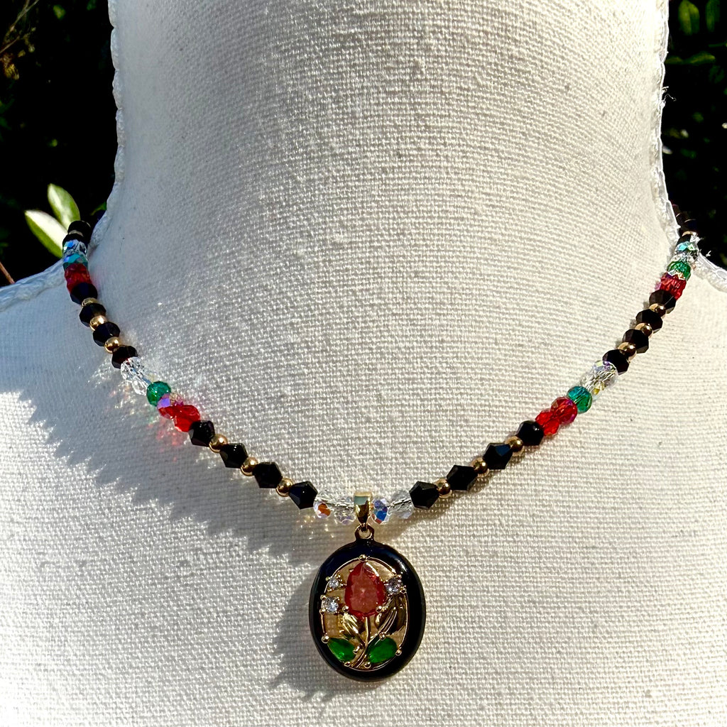 Necklace with colorful red and black beads and a decorative floral pendant on a white mannequin.