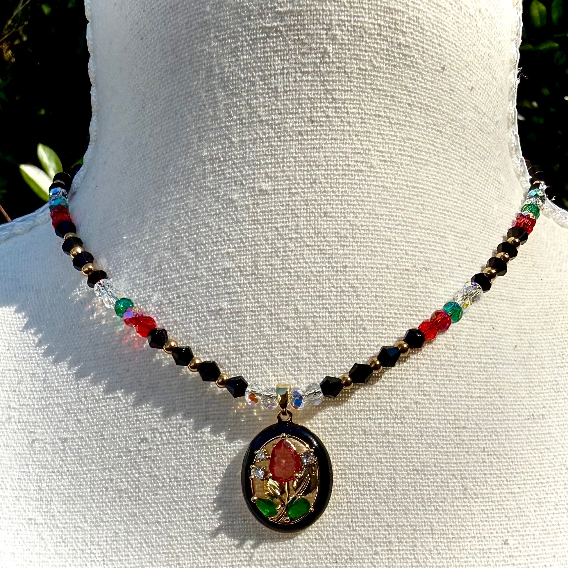 Necklace with colorful red and black beads and a decorative floral pendant on a white mannequin.