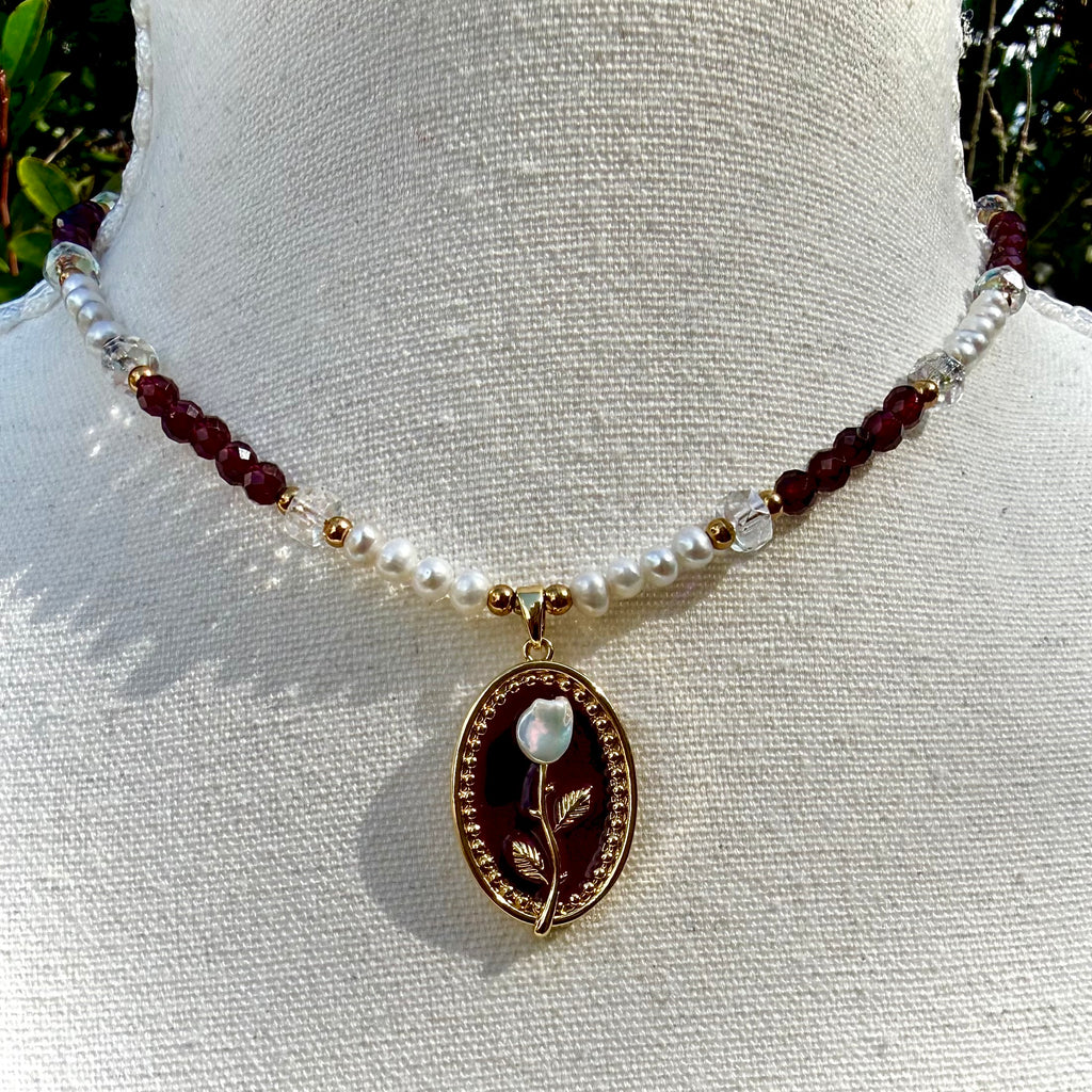 Necklace with pearl and red bead chain on a mannequin bust.